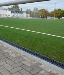 Starting at the trash boxes, the channel lines were placed along the edge of the playing field on a concrete foundation and stabilised with a concrete back support.